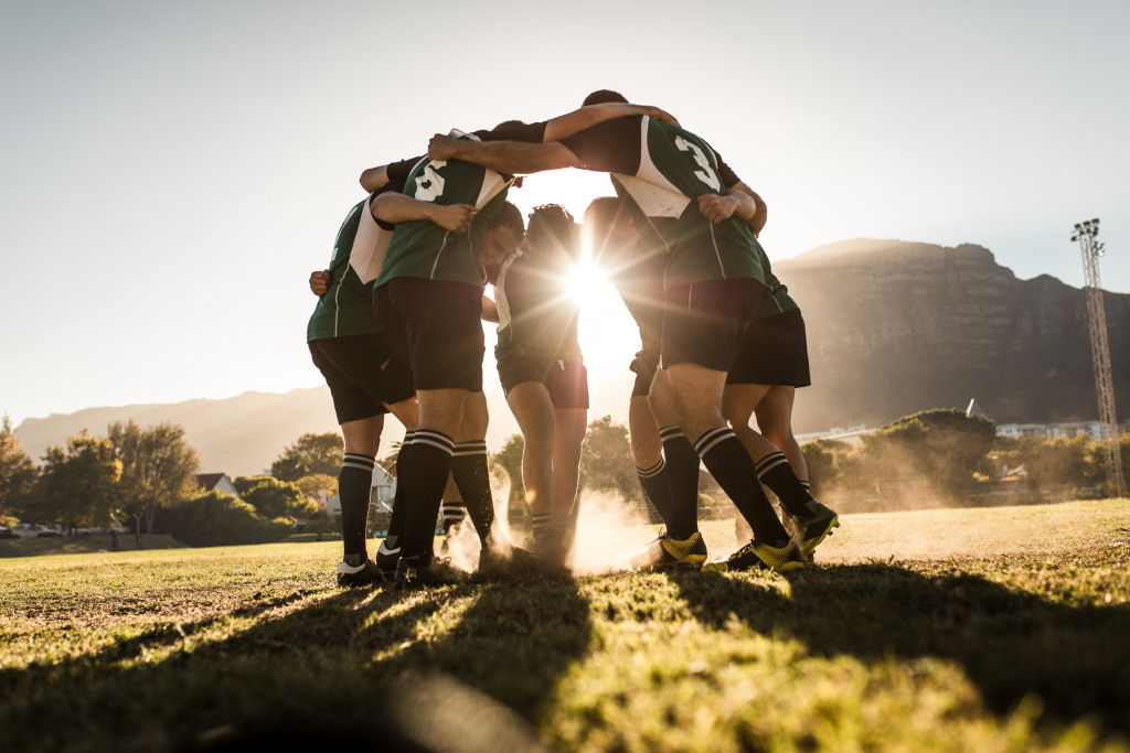 Eine Gruppe Fußballer stehen am Feld und bilden einen Kreis.