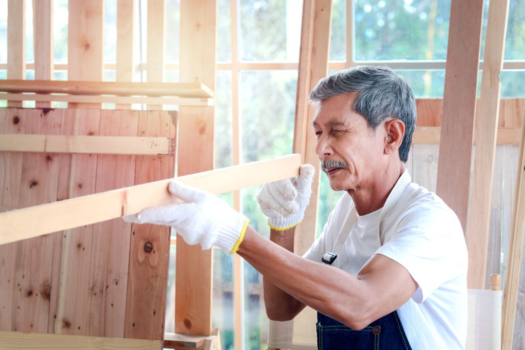 Handwerker schätzt die Länge von einem Stück Holz.