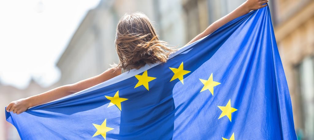 Ein Kind, das die EU-Flagge hintern seinem Rücken ausbreitet.
