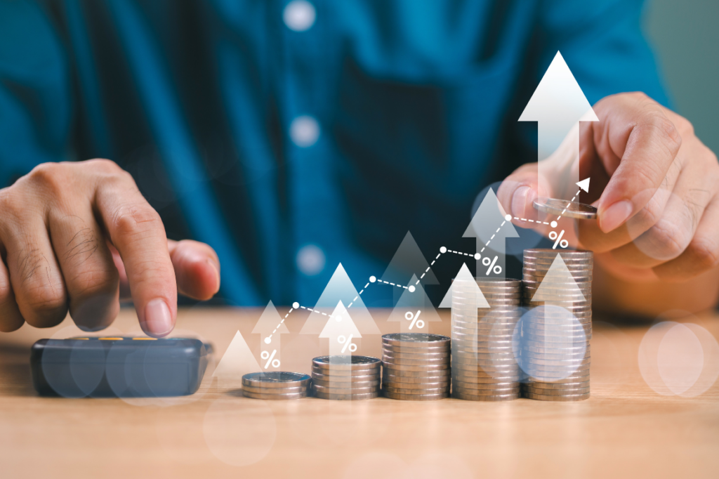 Münzstapel mit aufsteigenden Pfeilen und Prozentzeichen symbolisieren Preissteigerung und Inflation.