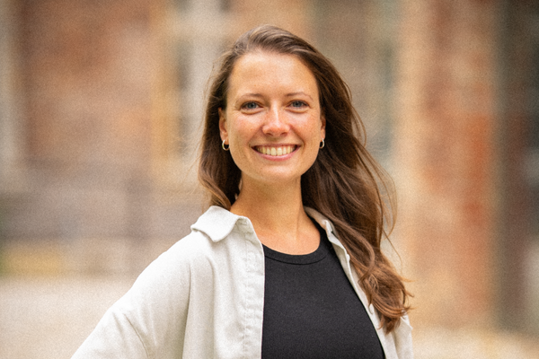 Porträt von Alina Schwadtke vor einer Ziegelwand, freundlich in die Kamera blickend.