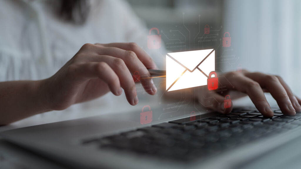 Person tippt auf Laptop mit schwebendem E-Mail-Symbol und roten Sicherheitsschlössern – Symbolbild für verschlüsselte Kommunikation oder Datensicherheit beim E-Mail-Versand.